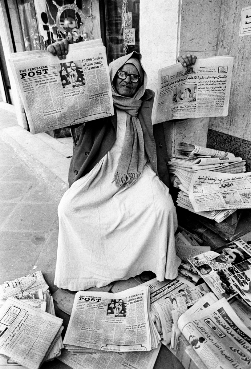 Mustapha, a newspaper vendor holds up the Jerusalem Post with the Egyptian Al-Ahram newspaper. Israeli newspapers were sold in Cairo after the Camp David agreement between Egypt and Israel was signed. : Sadat-Mubarak 1978-1981 : BILL FOLEY 