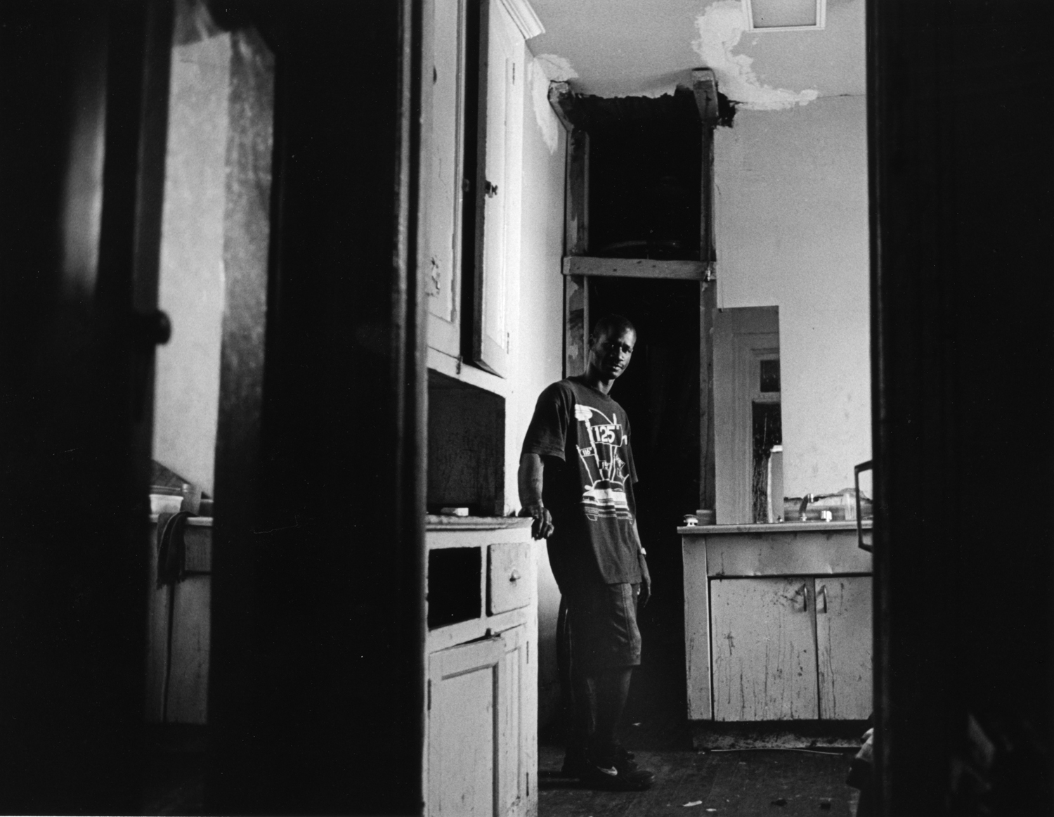 Robert looks through doorway in his unrenovated apartment 1996. : Carmel Hill Harlem NYC 1995-2000 : BILL FOLEY 