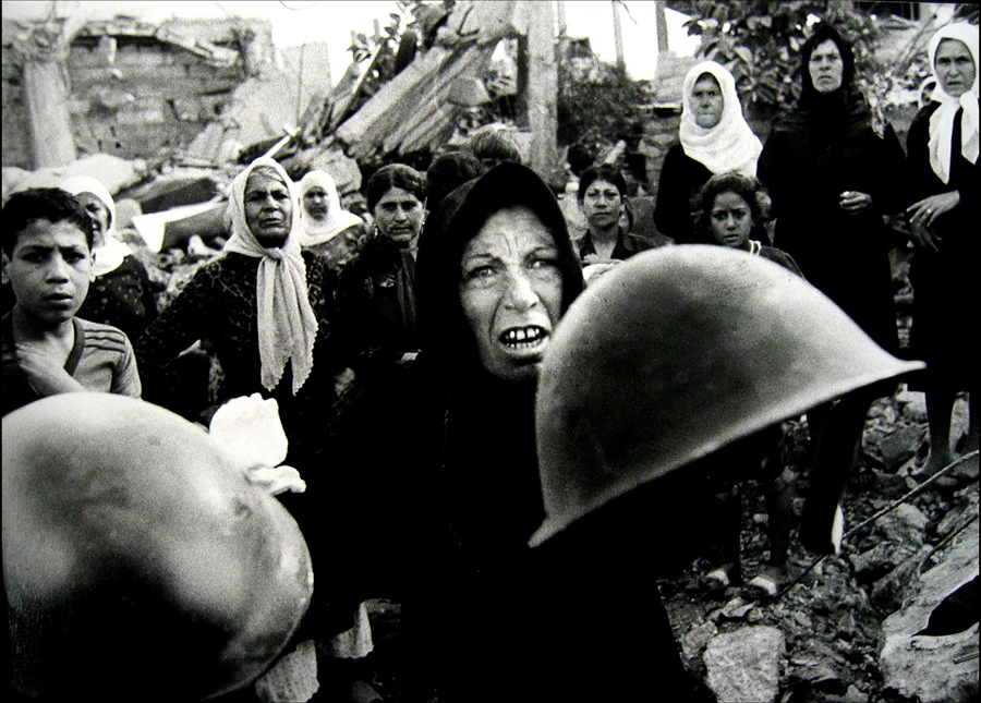 Palestinian woman, holds out helmets found in the Sabra-Chatilla camp after massacre, telling reporters these were worn by the killers. : Sabra Chatilla Massacre Beirut 1982 Pulitzer series : BILL FOLEY 