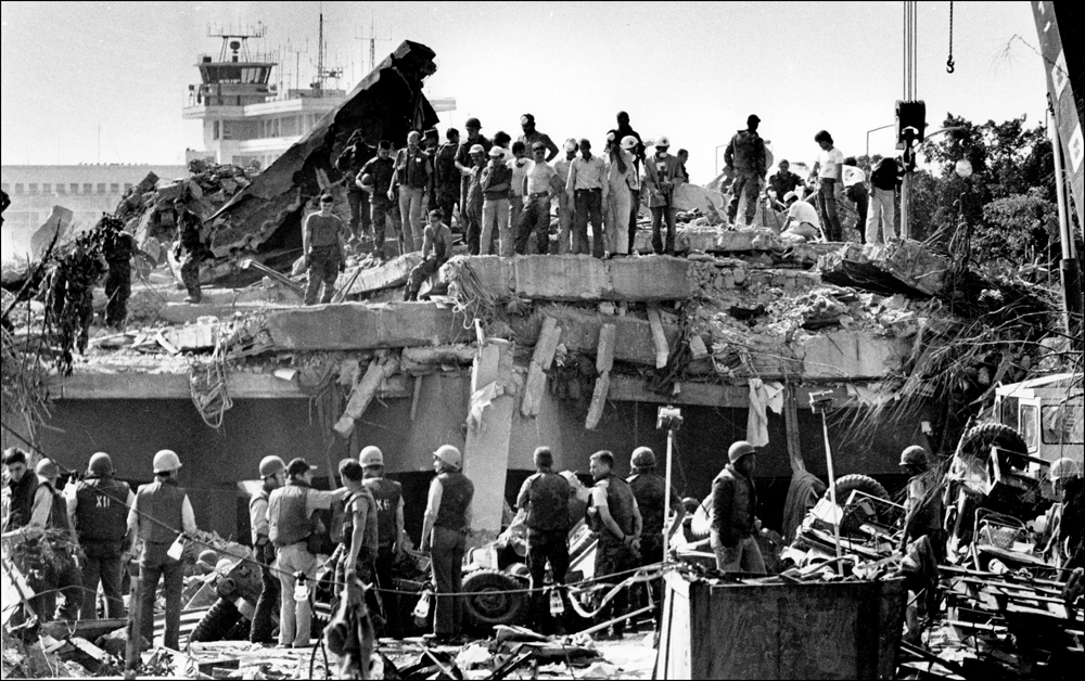Aftermath, clean up and search continues at the destroyed US Marine HQ at Beirut aiport, Oct. 1983. Beirut airport control tower seen in background. : USMC in Beirut 1982-1983 : BILL FOLEY 